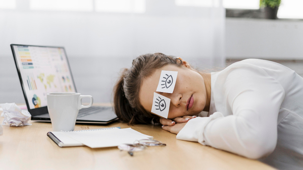 Tired-businesswoman-covering-her-eyes-with-drawn-eyes-on-paper